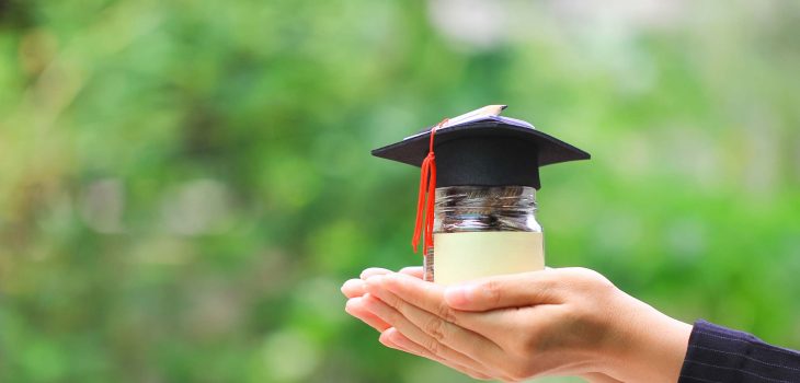 Hand holding jar with graduation cap.